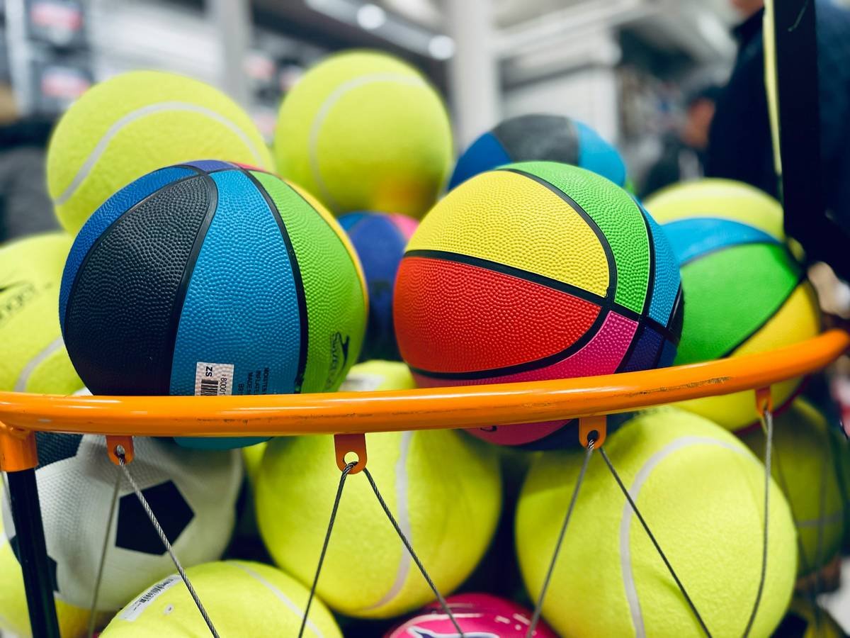 Stack of new padel balls in tubes labeled value bulk buy with tennis racket nearby